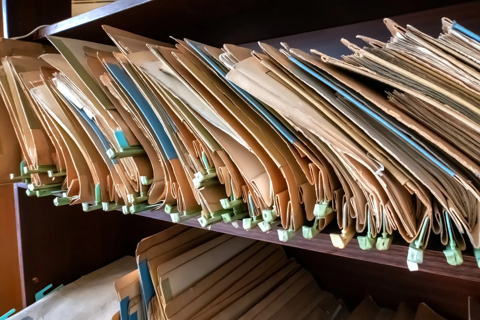 Regalfach mit dicht gestellten Aktenmappen mit Bändchen und Griffmarken